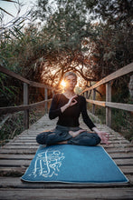 Load image into Gallery viewer, Sustainable hand tailored empowering and supporting small businesses and artisans for social impact and economic support. Local artisans are invovled every step of the way with this linen cotton fabric and silver embroidered with arabic calligraphy trimming inspired by healing mantras and chants of bija and chakra notes. Meditation, prayer and serenity mats or rugs. padded with local sourcing and suppliers. Sounds of Healing serenity mat by A'myn, Lady meditating at al azraq reserve in jordan