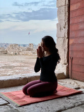 Load image into Gallery viewer, citadel jordan ummayyad palace in amman Jordan, roots serenity mat with lady meditating on it, saying a prayer. hand made and embroidered mindfully to create social impact and empower women refugees from palestine. artisans working to improve lives